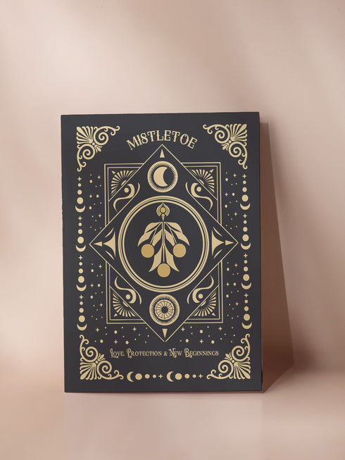 Mistletoe-themed holiday ritual card featuring a gold-stylized mistletoe design with celestial and ornate decorative accents on the front and an inside message explaining the mistletoe's historical significance and its use in Winter Solstice and Twelfth Night rituals for love, protection, and prosperity.
